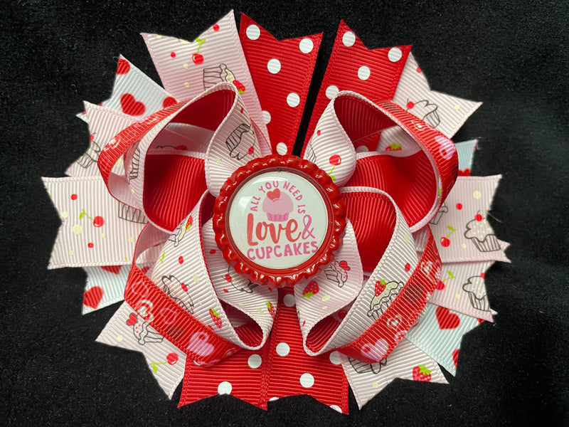 LAYERED MULTI COLOR AND VARIOUS STYLE RIBBONS BOW WITH ALL YOU NEED IS LOVE AND CUPCAKES BOTTLE CAP CENTER (Roughly 5” in length) - Lil Monkey Boutique
